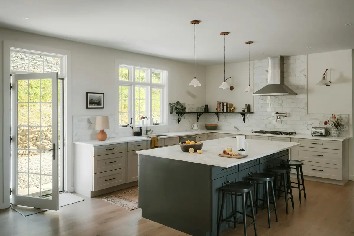 Large family kitchen with a dark island and stools, pale shaker cabinets, a marble splashback, pendant lights and a glazed door opening to the garden